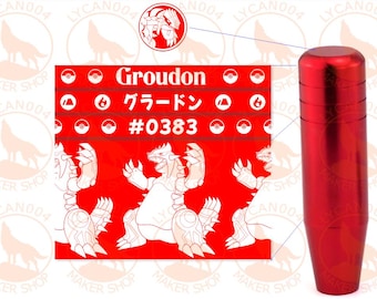 May include: A cylindrical red metal gear shift knob with a smooth finish. Next to it is a red rectangular graphic featuring the white text Groudon, the Japanese characters グラードン, and the number #0383, along with illustrations of the creature Groudon.
