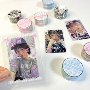 May include: An assortment of decorative washi tape rolls in various designs and colors, including floral patterns and geometric shapes. The image also features several photo cards with a young person, decorated with stickers and text.