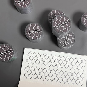 May include: A collection of gray washi tape rolls with a chain-link pattern and the text "SHOCKING PINK ROSE". A sheet of paper with a matching chain-link design is also present. The items are arranged on a gray surface.