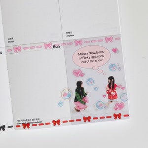 K&ouml;nnte beinhalten: Ein wei&szlig;er Hintergrund mit rosa und roten Schleifen und Text in Koreanisch und Englisch. Der Text lautet "Make a NewJeans or Binky light stick out of the snow". Auf dem Bild sind zwei M&auml;dchen zu sehen, eines tr&auml;gt ein gr&uuml;n-rosa Outfit und das andere ein rot-wei&szlig;es Outfit. Sie stehen in einer Schneelandschaft mit rosa Herzen und blauen Blasen.