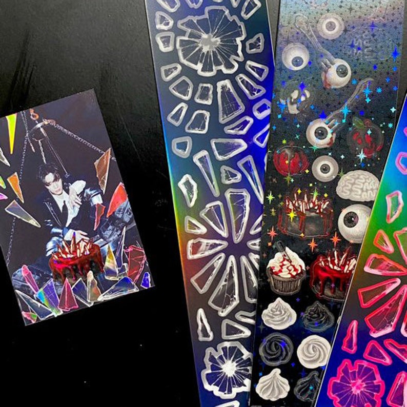 May include: Three holographic sticker sheets with various designs. The first sheet features a pattern of broken glass shards. The second sheet features a pattern of eyes, brains, and cakes. The third sheet features a pattern of colorful swirls.