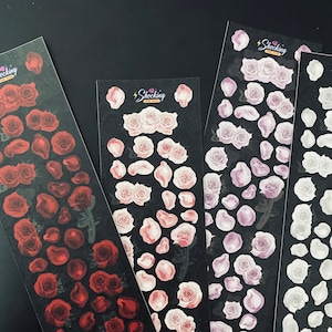 May include: Three sheets of stickers featuring floral designs. The stickers are on a black background. The first sheet features red roses and rose petals. The second sheet features pink roses and rose petals. The third sheet features purple roses and rose petals. Each sheet has the text "Shocking" printed on it.