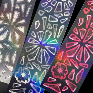 May include: Three sheets of iridescent sticker paper with a design of broken glass pieces in white, blue, and pink.