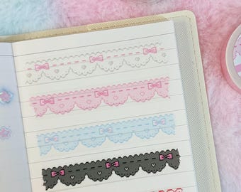 May include: A collection of six decorative washi tapes featuring different patterns, including lace, bows, and gingham. The tapes are displayed on a white page in a notebook.