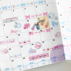 K&ouml;nnte beinhalten: Ein rosa und blauer Kalender mit Aufklebern mit Schleifen, Herzen, Kirschen und einem Comic-Charakter. Der Kalender hat den Text "DANIELLE BIRTHDAY" und "공주님 너무 아름다우세요*" geschrieben.