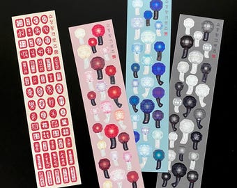 May include: Four sticker sheets with various designs. One sheet features red characters, while the others showcase colorful lantern-like illustrations. The text "쇼킹핑크로즈" is printed on three of the sheets. The stickers are arranged on a black background.