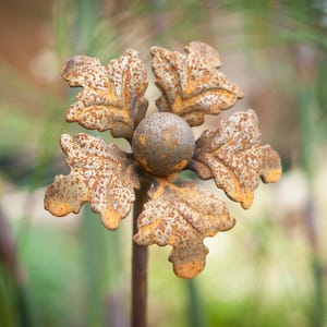 May include: A rusty metal flower with five petals and a round centre. The flower is a decorative garden ornament.
