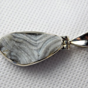 May include: A silver pendant necklace featuring a light blue and white agate stone with a swirling pattern. The stone is set in a silver bezel and hangs from a silver chain.