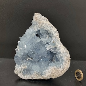 May include: A large blue celestite geode with a rough exterior and a crystal-filled interior. The geode is about the size of a small grapefruit.