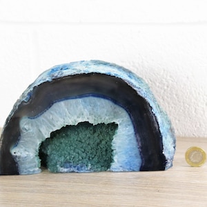 Puede incluir: Una geoda de ágata azul y verde con un centro hueco. La geoda mide aproximadamente 15 cm de alto y 10 cm de ancho.
