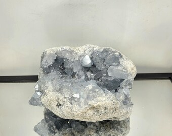 May include: A large, gray celestite geode with a natural opening revealing a cluster of sparkling, light blue crystals.