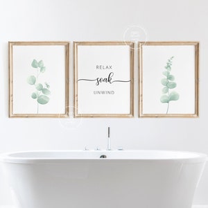 May include: Three framed prints with a white background and a light green eucalyptus leaf design. The center print has the text "Relax soak unwind" in black script font.