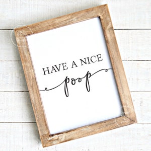 May include: A framed print with the text "Have a nice poop" in a cursive font. The frame is made of wood and has a light brown finish.