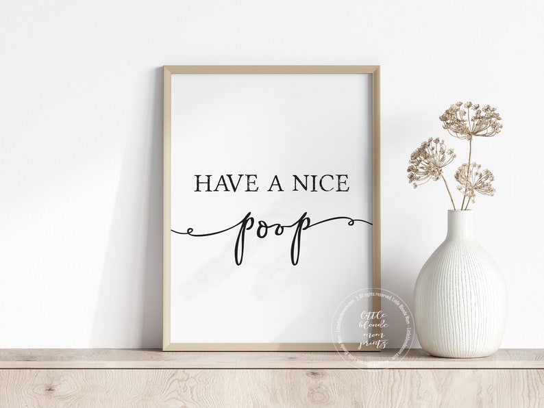 May include: A framed print with the text "Have a nice poop" in black cursive font on a white background. The frame is a light brown wood.