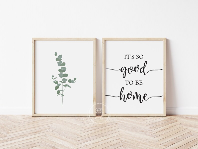 Puede incluir: Dos impresiones enmarcadas, una con una rama de eucalipto verde y la otra con el texto "It's so good to be home".