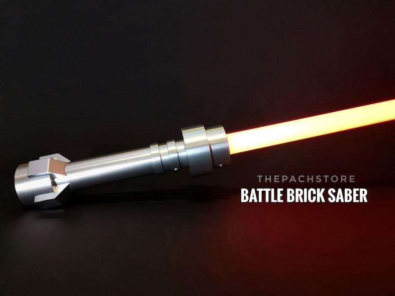 May include: A silver lightsaber with a red blade. The lightsaber is made of metal and has a textured handle. The text "THEPACHSTORE BATTLE BRICK SABER" is visible in the image.