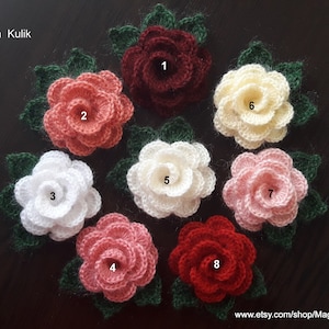 May include: Eight crocheted flowers in various colors, including red, pink, white, and cream. Each flower has a green leaf attached. The flowers are numbered 1 through 8.