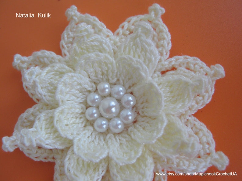 May include: A white crocheted flower with a center of white pearl beads.