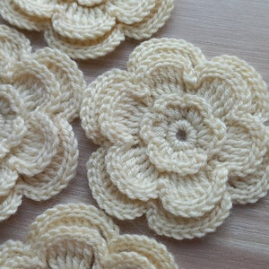May include: Four crocheted cream-colored flowers with a layered design.