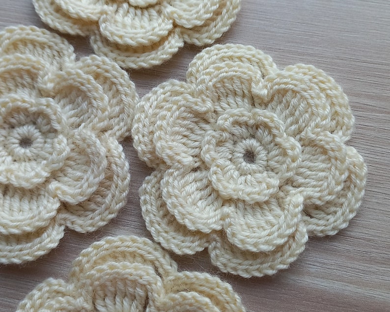 May include: Four crocheted cream-colored flowers with a layered design.