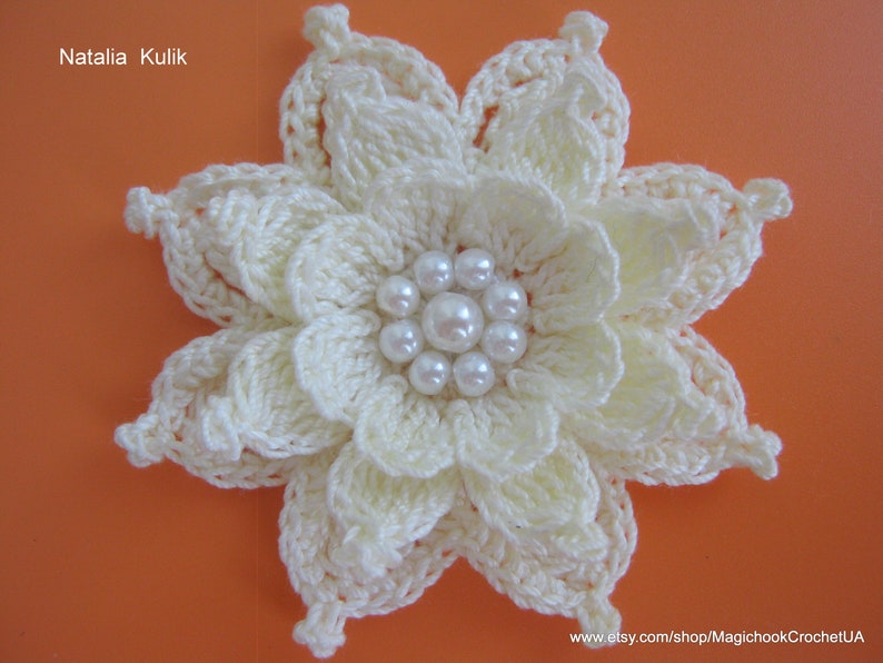 May include: A white crocheted flower with a center of white pearl beads.