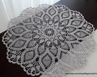May include: A white crocheted doily with a delicate floral pattern. The doily is round and has a scalloped edge.
