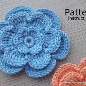May include: A crocheted flower pattern with instructions. The flower is light blue and has five petals. The pattern is available for purchase on Etsy.