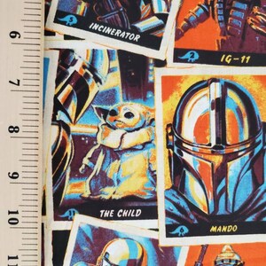 May include: A colorful fabric with a repeating pattern of trading cards featuring characters from the Star Wars universe. The cards feature images of characters like The Child, Mando, IG-11, and Incinerator. The cards have a vintage look with a white background and a yellow border.