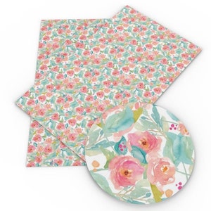 May include: A sheet of white faux leather with a pink and green floral pattern. The pattern features small pink flowers and green leaves. The sheet is folded in half and there is a close-up of a larger pink flower with green leaves in the corner.