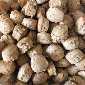 May include: A bowl filled with small, round, light brown cookies. The cookies are all about the same size and shape, and they appear to be made with a simple dough.