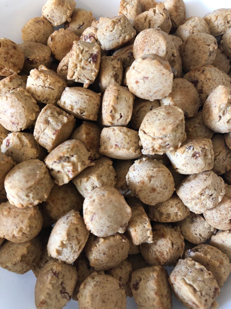 May include: A bowl filled with small, round, light brown cookies. The cookies are all about the same size and shape, and they appear to be made with a simple dough.