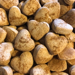 K&ouml;nnte beinhalten: Ein Haufen herzf&ouml;rmiger Kekse mit einer Zimt-artigen Best&auml;ubung. Die Kekse sind hellbraun und haben eine leicht raue Textur.