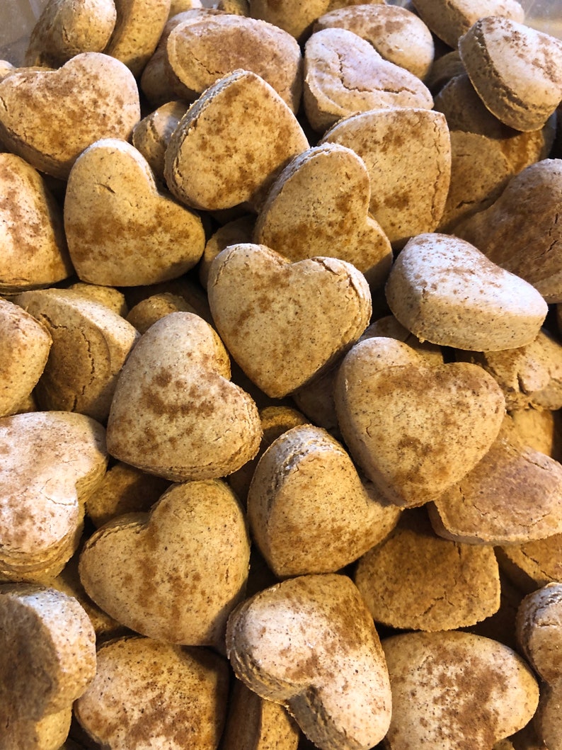 K&ouml;nnte beinhalten: Ein Haufen herzf&ouml;rmiger Kekse mit einer Zimt-artigen Best&auml;ubung. Die Kekse sind hellbraun und haben eine leicht raue Textur.