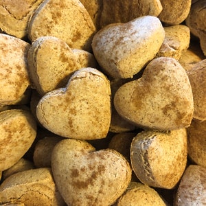 K&ouml;nnte beinhalten: Nahaufnahme eines Stapels herzf&ouml;rmiger Kekse, die alle mit einer hellbraunen Zimtzuckerglasur bedeckt sind.