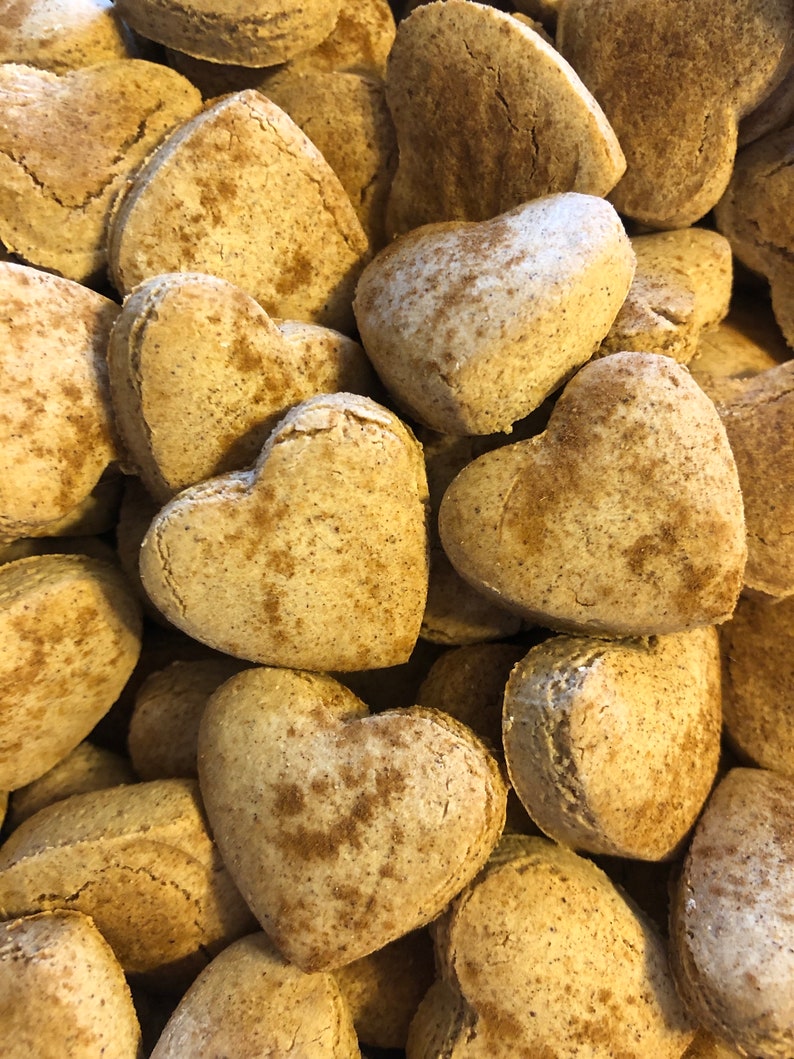 K&ouml;nnte beinhalten: Nahaufnahme eines Stapels herzf&ouml;rmiger Kekse, die alle mit einer hellbraunen Zimtzuckerglasur bedeckt sind.