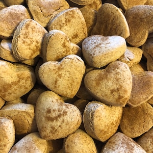 K&ouml;nnte beinhalten: Ein Nahaufnahmebild eines Stapels herzf&ouml;rmiger Kekse. Die Kekse sind hellbraun und haben eine gesprenkelte Oberfl&auml;che, was darauf hindeutet, dass sie mit Zimt oder anderen Gew&uuml;rzen hergestellt wurden.