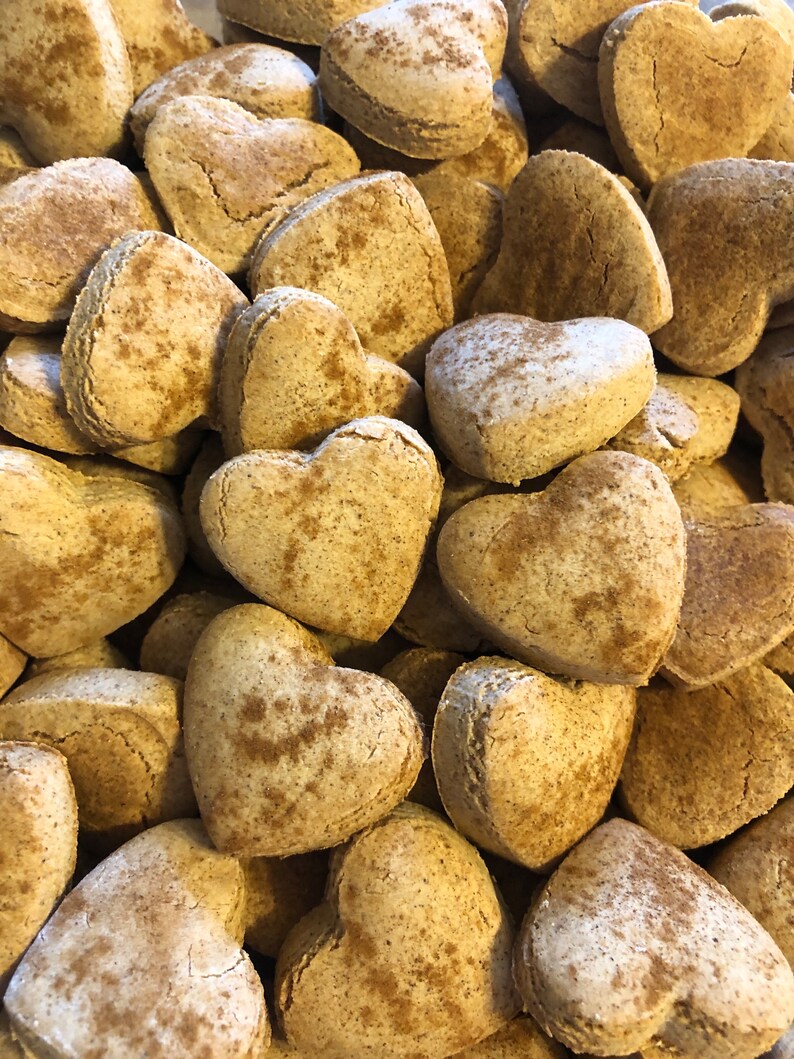 K&ouml;nnte beinhalten: Ein Nahaufnahmebild eines Stapels herzf&ouml;rmiger Kekse. Die Kekse sind hellbraun und haben eine gesprenkelte Oberfl&auml;che, was darauf hindeutet, dass sie mit Zimt oder anderen Gew&uuml;rzen hergestellt wurden.