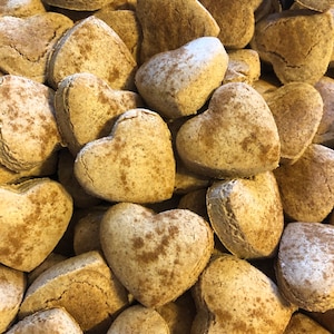 K&ouml;nnte beinhalten: Ein Nahaufnahmebild eines Stapels herzf&ouml;rmiger Kekse. Die Kekse sind hellbraun und haben eine gesprenkelte Textur.