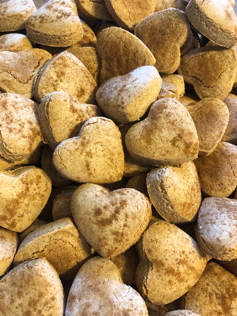 K&ouml;nnte beinhalten: Ein Nahaufnahmebild eines Stapels herzf&ouml;rmiger Kekse. Die Kekse sind hellbraun und haben eine gesprenkelte Textur.