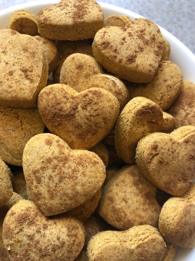 K&ouml;nnte beinhalten: Eine Sch&uuml;ssel gef&uuml;llt mit herzf&ouml;rmigen Keksen, die mit Zimt best&auml;ubt sind. Die Kekse sind hellbraun und haben eine leicht raue Textur.