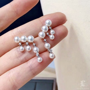 May include: A pair of pearl and diamond earrings. The earrings feature a cluster of white pearls with a diamond accent.