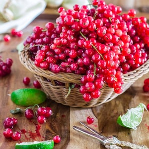 Może przedstawiać: Koszyk wiklinowy wypełniony czerwonymi porzeczkami, otoczony plastrami limonki i czerwonymi porzeczkami na drewnianej powierzchni.