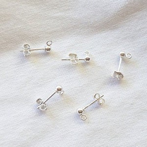 May include: Five silver earring backs, each with a small loop and a post for attaching an earring.