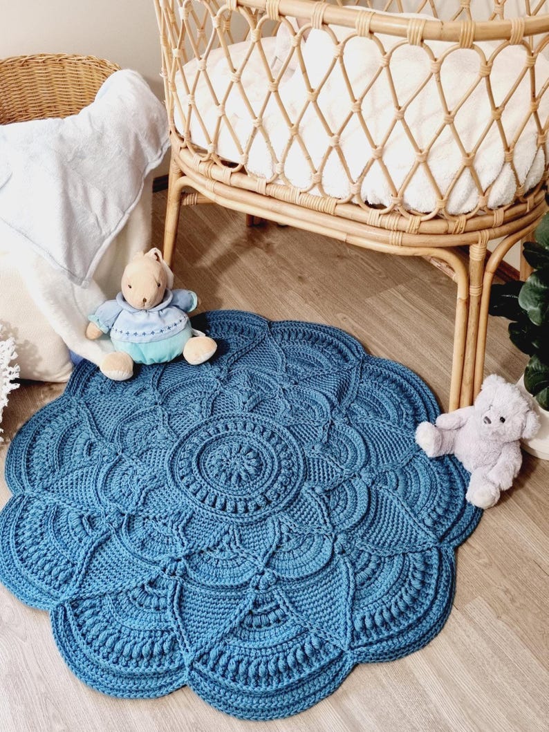 Floral, blue crochet floor rug in front of a baby bassinet.