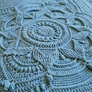 Crochet blanket laying on queen-sized bed.