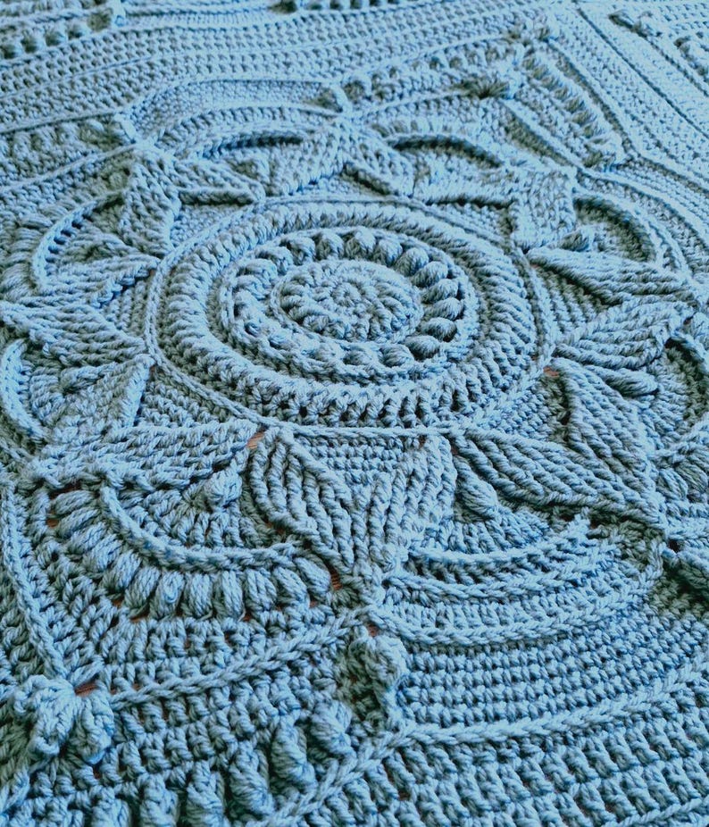 Crochet blanket laying on queen-sized bed.