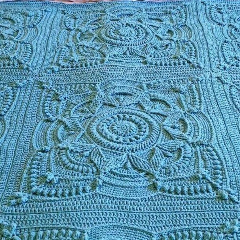 Crochet blanket laying on queen-sized bed.