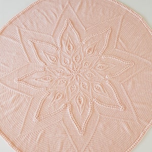 Könnte beinhalten: Eine rosa gehäkelte Babydecke mit einem Sternmuster in der Mitte.