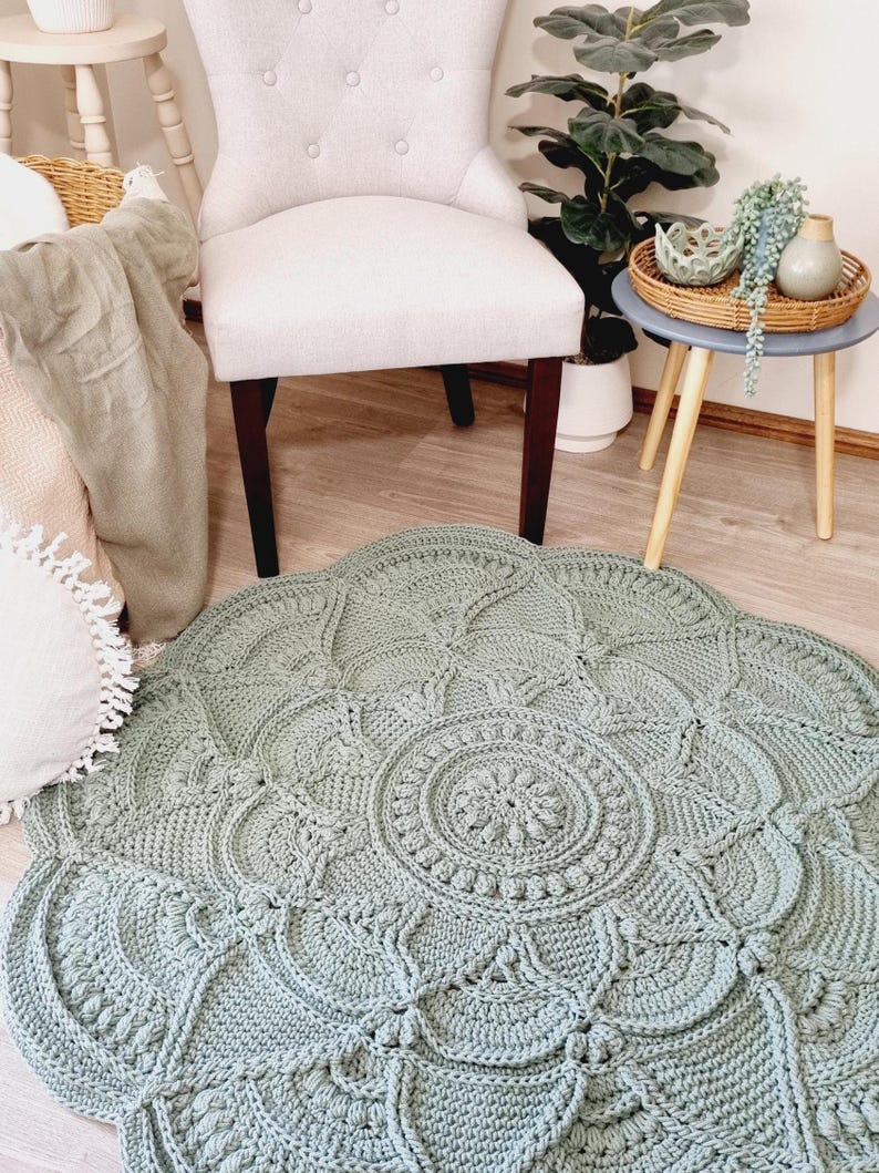 Floral, green crochet floor rug in front of a chair and coffee table.