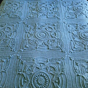 Crochet blanket laying on queen-sized bed.